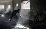 Un Palestinien nettoie à la pelle les décombres d'un bâtiment touché par un bombardement à Nousseirat, dans le centre de la bande de Gaza, le 12 août 2024