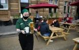 Une serveuse apporte des boissons à des clients à la terrasse d'un pub de Glasgow, le 26 avril 2021 en Ecosse