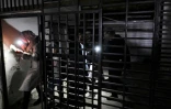 Des personnes utilisent leurs téléphones portables pour s'éclairer dans une cellule de la prison gérée par la "branche de sécurité de la Palestine", le 13 décembre 2024 à Damas