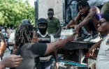 Un homme donne un pack de bouteilles d'eau lors d'une distribution de vivres aux Cayes, ville ravagée par le séisme, le 20 août 2021