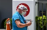 Un soignant regarde son téléphone à l'extérieur du service des urgences de l'hôpital de Coral Gables près de Miami le 30 juillet 2020 en pleine épidémie de coronavirus