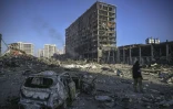Un militaire ukrainien devant le centre commercial Retroville dévasté par un bombardement, à Kiev le 21 mars 2022