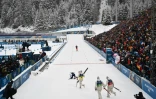 Quentin Fillon Maillet, Emilien Jacquelin et Fabien Claude se précipitent vers Eric Perrot, le dernier relayeur français qui vient de franchir en tête la ligne d'arrivée du relais des JO-2026 le 17 février 2026 à Anterselva
