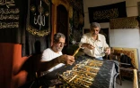 L'Egyptien Ahmed Othmane supervise la broderie d'une épaisse étoffe noire de versets coraniques avec des fils d'or, le 15 juin 2022, au Caire