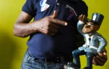 L'acteur ivoirien Michel Gohou pose avec une statue du gendarme de Abobo, Ă Abidjan le 20 novembre 2019.