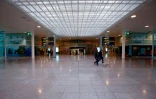Deux personnes promènent un chien dans un terminal désert de l'aéroport de Barcelone, le 16 mars 2020.