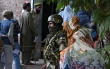 Un agent de sécurité indien monte la garde alors que les électeurs font la queue pour voter dans un bureau de vote lors de la première phase des élections législatives à Pulwama, au sud de Srinagar, le 18 septembre 2024