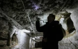 Un scientifique examine les formes de glace qui sortent du pergélisol dans un tunnel souterrain à l'Institut du pergélisol à Iakuutsk, le 28 mars 2025 en Sibérie orientale