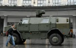 Un homme marche près d'un véhicule militaire garé devant la gare centrale de Bruxelles le 21 novembre 2015