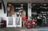 Des employés installent des panneaux en bois pour protéger les vitrines d'une boutique avant l'arrivée de l'ouragan Laura, le 25 août 2020 à Lake Charles en Louisiane
