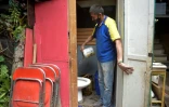Jorge Ariza verse de l'eau dans la cuvette des toilettes de sa maison, construite de bric et de broc, le 26 mai 2020 à Bogota, en Colombie