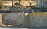 Des Palestiniens derrière des blocs de béton à l'entrée principale de Hébron, la plus grande ville de la Cisjordanie occcupée, le 2 juillet 2016