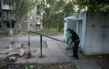 Un habitant pompe de l'eau dans une rue de Toretsk, dans la région de Donetsk en Ukraine, le 29 juillet 2024