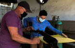 Le carrossier Pedro Manso (g) aide son apprentie Lemaydi Madrigal (d) dans son atelier de Placetas, dans la province de Villa Clara, le 24 avril 2021 à Cuba