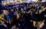 Les employés du centre d'appels surfent sur leurs téléphones portables alors qu'ils se rassemblent devant leur immeuble de bureaux après les secousses du tremblement de terre à Cebu, dans le centre des Philippines, le 30 septembre 2025