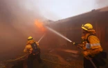 Des pompiers tentent d'éteindre les flammes dévorant une maison du quartier de Pacific Palisades, aux portes de Los Angeles, le 7 janvier 2025