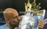 L'entraîneur espagnol de Manchester City Pep Guardiola embrasse le trophée de la Premier League, après avoir remporté le titre, lors de la 38e et dernière journée en battant à domicile Aston Villa (3-2), le 22 mai 2022 à l'Etihad Stadium