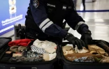 Un douanier inspecte les bagages de passagers à l'aéroport de Roissy-Charles-de-Gaulle, au nord de Paris, le 21 mars 2025 