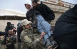 Un combattant des Forces démocratiques syriennes (FDS) aide un homme qui a fui les zones de combats entre les FDS et le groupe Etat islamique (EI), près de Baghouz, dans l'est de la Syrie, le 14 février 2019