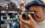 Yoshinobu Ishikawa, patron de Popeye Camera, un magasin spécialisé dans la photographie argentique, teste un appareil photo d'occasion à vendre, le 9 juillet 2024 à Tokyo