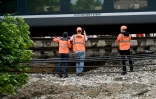 Des employés SNCF travaillent à côté d'un TGV reliant Toulouse à Bordeaux dont les ballasts situés sous la voie ferrée ont été emportés par le débordement d'un ruisseau en raison des intempéries, le 20 mai 2025, à Tonneins, dans le Lot-et-Garonne