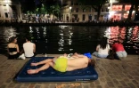 Un jeune se rafraïchit le long du canal Saint-Martin en pleine canicule à Paris le 25 juin 2026