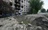 Un cratère de bombe devant un immeuble endommagé, le 30 juin 2022 à Seversk, dans la région de Donetsk, en Ukraine