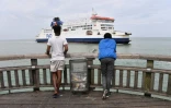 Des migrants venant d'Erythrée regardent un ferry arrivant de Grande-Bretagne accoster au port de Calais, le 12 août 2019