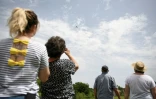 Des fidèles de l'église de Saint-Avit observe le père Pierre Hoan qui bénit les champs depuis un avion Piper, le 21 mai 2022 à Castelsarrasin, dans le Tarn-et-Garonne 
