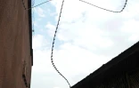 Des hommes passent devant des fils de fer barbelé utilisés pour sécuriser la cour de la prison de Muzenze à Goma, en RDCongo le 21 novembre 2012