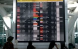 Des voyageurs consultent un tableau d'information affichant les vols annulés après l'éruption du mont Lewotobi Laki-Laki, à l'aéroport international Ngurah Rai de Tuban, près de Denpasar, sur l'île touristique de Bali, le 18 juin 2025 en Indonésie