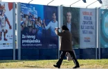Un homme passe devant une affiche électorale du président croate sortant et candidat à la présidentielle du SDP, Zoran Milanovic (d.), et du candidat du parti du HDZ, Dragan Primorac (g.), à Zagreb, le 27 décembre 2024