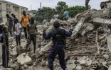 Un policier parle à des jeunes qui ramassent du métal dans les décombres de maisons en cours de démolition à Kinshasa, le 8 mai 2025 à Kinshasa, en RDC