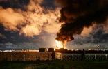 Des personnes observent un terminal pétrolier en feu à la suite d'une attaque aérienne à Saint-Pétersbourg, le 18 octobre 2026, dans le contexte du conflit russo-ukrainien en cours