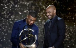 L'attaquant Kylian Mbappé (g), avec le trophée de meilleur joueur de Ligue 1, aux côtés de l'ancien joueur Thierry Henry, lors de la cérémonie des Trophées UNFP, à Paris, le 15 mai 2022