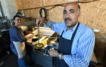 Jawad (g) et Zainab Al-Khajee, couple de journalistes irakiens réfugiés en France, préparent des plats irakiens, le 23 juin 2018 dans le snack de Darwin, un espace associatif sur les bords de la Garonne, à Bordeaux