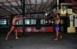 Deux boxeurs professionnels, Pongpisarn Sunyong (à gauche) et Sarawut Prohmsut, à l'entraînement avec un masque et en respectant la distanciation sociale dans une salle de muay thaï de Bangkok le 9 avril 2020