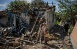 Un couple sort des valises depuis leur maison détruite à Vilkhivka, près de Kharkiv, est de l'Ukraine, le 14 mai 2022
