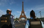 Un membre d'une force de sécurité qatarie (gauche) et une gendarme française se tiennent près de la tour Eiffel, le 18 juillet 2024 à Paris