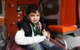 Une enfant mange un sandwich dans une ambulance à son arrivée à Qalaat al-Madiq, localité de la province syrienne de Hama, après son évacuation d'un secteur rebelle de la Ghouta orientale, le 28 mars 2018