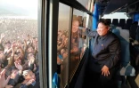 Photo diffusée par l'agence officielle nord-coréenne Korean Central News Agency (KCNA) le 8 octobre 2015 montrant le dirigeant Kim Jong-Un saluant la foule depuis un autobus pendant qu'il inspecte un nouveau village Paekhak-dong dans le district de Sonbong