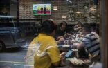 Télévision diffusant la cérémonie du 25e anniversaire de la rétrocession de Hong kong dans un restaurant de la ville, le 1er juillet 2022