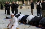Des fidèles musulmans prient pendant que des soldats israéliens escortent des visiteurs juifs sur l'esplanade des mosquées, le 9 avril 2023 à Jérusalem