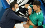Le Serbe Novak Djokovic reçoit des soins, lors de son match du 3e tour contre l'Américain Taylor Fritz à l'Open d'Australie, le 12 février 2021 à Melbourne