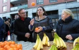 Mary Lou McDonald (c), la cheffe du Sin Fein, jongle avec des oranges en parlant avec une vendeuse de fruits (d), le 10 février 2020 à Dublin