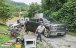 Un couple tente de sauver des meubles pendant des inondations à Jackson, le 28 juillet 2022 dans le Kentucky