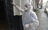 Un employé désinfecte l'entrée d'un immeuble pendant l'épidémie de coronavirus, le 20 mars 2020 à Alger