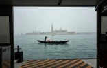 Un gondolier manoeuvre sa gondole vide sur le bassin de Saint-Marc, avec l'église San Giorgio maggiore en arrière-plan, le 6 février 2021 à Venise (Italie)
