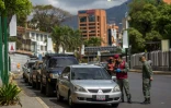 Des policiers contrôlent les automobilistes qui attendent pour faire le plein le 23 mars 2020 à Caracas
