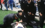 Des policiers aident un supporteur blessé dans le stade de Hillsborough, le 15 avril 1989 à Sheffield, au Royaume-Uni